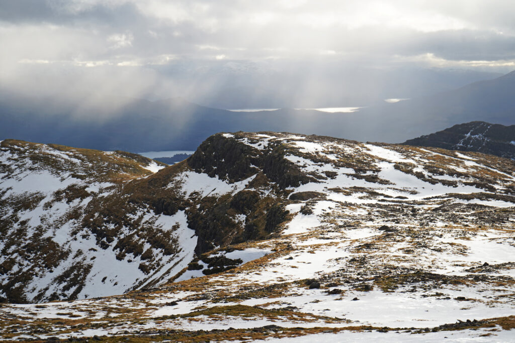 Bright white snow on Highland mountain peaks against a stormy winter sky