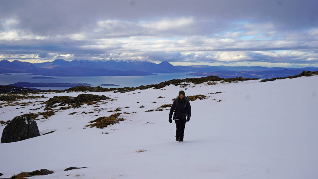 Wide view of the Scottish Highlands with snow-topped mountains, deep blue lochs and autumn colours